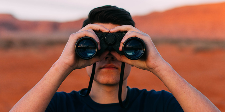 man looking through binoculars. best edibles for migraines online. Do edibles help with migraines?