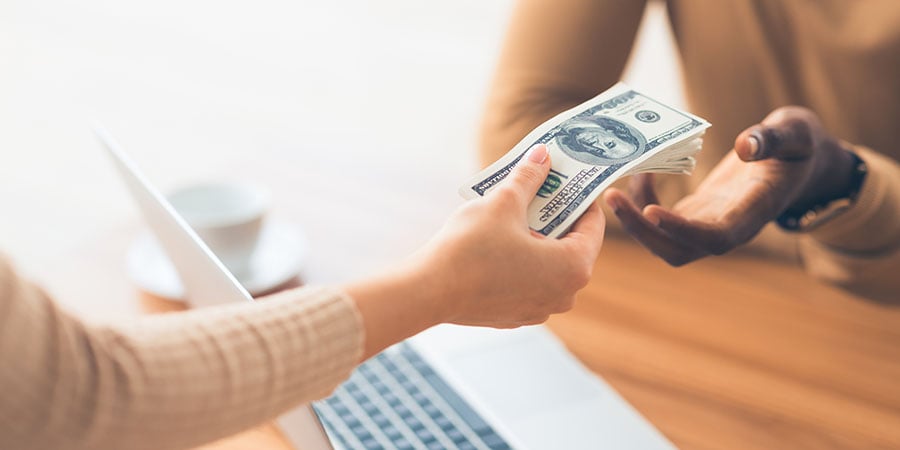 Woman handing cash to a cashier.
